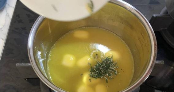 Adding chopped rosemary leaves to melted butter