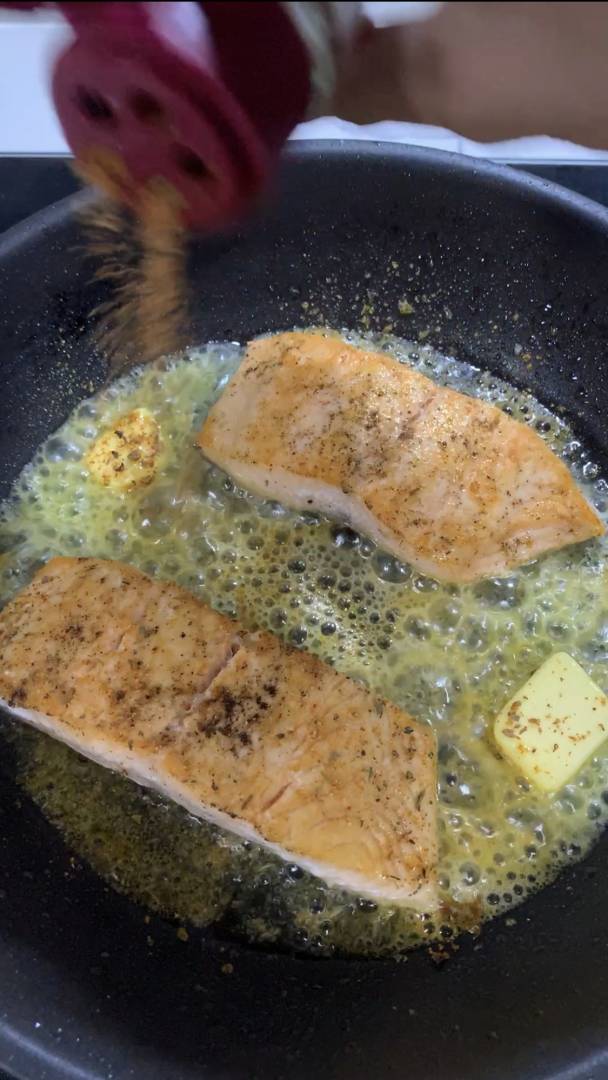 adding butter to fry salmon