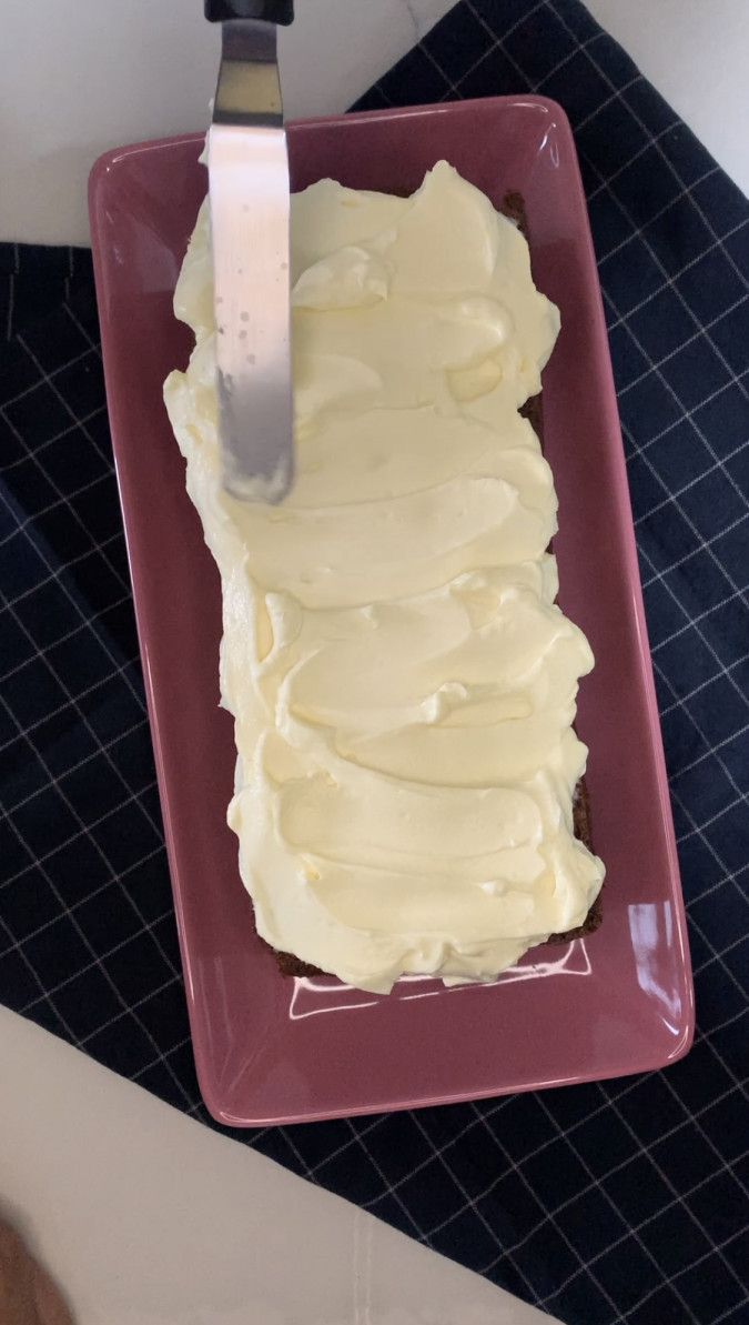 frosting a carrot loaf cake with cream cheese frosting